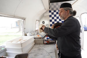 Barry stretches dough inside the Fire on the Bluff Airstream pizza kitchen Photo inside Airstream of Barry stretching pizza dough